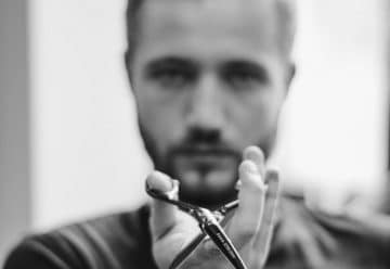 shallow focus photo of man holding scissors